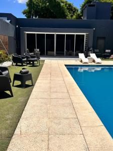 a backyard with a pool and chairs and a house at Residencia Dos Soles 2.0 in Resistencia