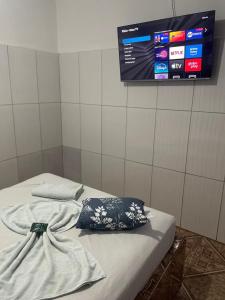 a bed with a pillow and a tv on a wall at Pousada Rosario in Malhada dos Bois
