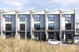 an apartment building with cars parked in front of it at Private ensuite room on the beach in Christchurch