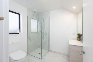 a bathroom with a shower with a toilet and a sink at Private ensuite room on the beach in Christchurch