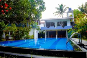 a swimming pool in front of a house at Casa Hikka Villa in Sinigama