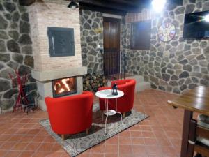 La Hoya的住宿－La Majada de la Covatilla，一间设有两张红色椅子和壁炉的房间