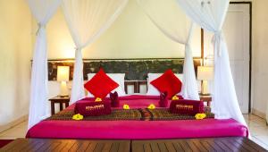 a bedroom with a large pink bed with red pillows at Kelimutu Crater Lakes Ecolodge in Kelimutu