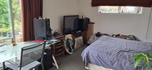 a bedroom with a bed and a desk and a deskablish at Private cabin in Whitianga