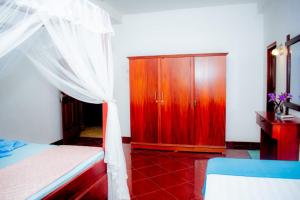 a bedroom with a bed and a wooden cabinet at Casa Hikka Villa in Sinigama +22 photos