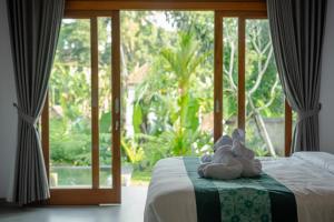 a bed with a teddy bear on it in front of a window at Wanasari Villa in Tampaksiring