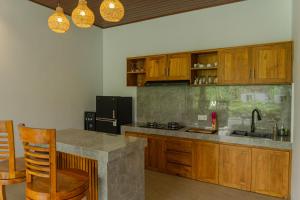 a kitchen with wooden cabinets and a counter top at Wanasari Villa in Tampaksiring