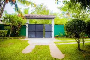 a green garage with a blue door in a yard at Casa Hikka Villa in Sinigama