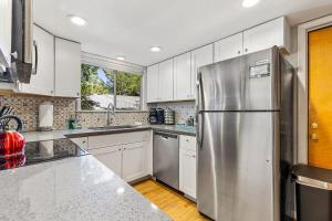 a kitchen with a stainless steel refrigerator and white cabinets at High Pines Abode in Flagstaff