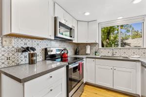 a white kitchen with white cabinets and a window at High Pines Abode in Flagstaff +20 photos