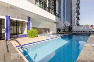 a large swimming pool in front of a building at Flat Novo1 - Café, Cama Queen, Ar, Estac e Internet in Barueri
