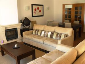 a living room with a couch and a fireplace at Praia Del Rey Seaview Apartment in Casal da Lagoa Seca
