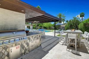 an outdoor kitchen with a grill and a table and chairs at Palm 57 - Alice Lodging in Palm Springs