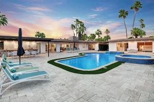 a swimming pool with chairs and an umbrella on a patio at Palm 57 - Alice Lodging in Palm Springs