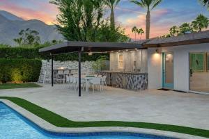 a patio with a table and a kitchen and a pool at Palm 57 - Alice Lodging in Palm Springs