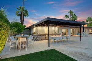 a patio with tables and chairs and a building at Palm 57 - Alice Lodging in Palm Springs