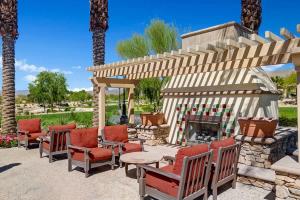 a patio with chairs and a fireplace and palm trees at Sun City Fun - Alice Lodging in Indio