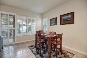 a dining room with a table and chairs and windows at Sun City Fun - Alice Lodging in Indio