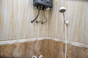 a bathroom with a shower with a hose attached to the wall at RedDoorz at Dieng 0KM in Diyeng +78 photos