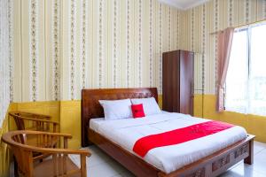 a bedroom with a bed and a chair in it at RedDoorz at Dieng 0KM in Diyeng