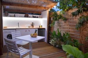 a patio with a table and chairs on a wooden deck at Le Fare de la Baleine in Punaauia