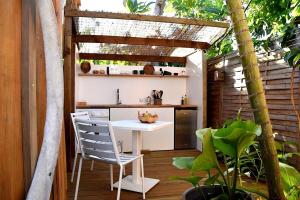 an outdoor kitchen with a white table and chairs at Le Fare de la Baleine in Punaauia