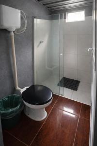 a bathroom with a black toilet and a shower at Itaúna Surf Camping in Saquarema