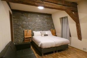 a bedroom with a large bed with a stone wall at Schmiede Hotel in Schoenberg