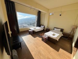 a room with two beds and a large window at The Khaar in Tawang