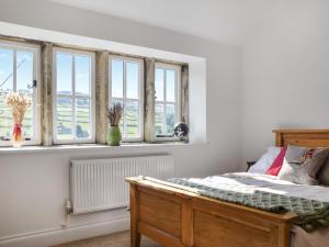 a bedroom with white walls and windows and a bed at Kestrel Cottage in Holmfirth