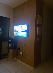 a room with a tv on a wall with a chair at Ap charmoso in Mossoró