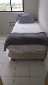 a bed sitting in a room with a window at Ap charmoso in Mossoró