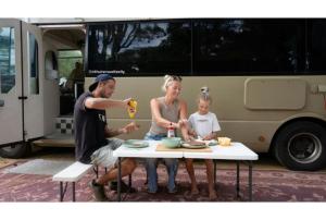 a man and a woman sitting at a table with a child at Discovery Parks Margaret River in Cowaramup