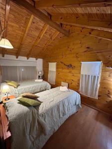a bedroom with two beds in a log cabin at Rincon de Ñires cabaña 4 in San Martín de los Andes
