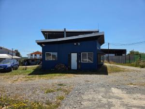 a blue house sitting on top of a gravel lot at Cabañas de Turismo Berolav7 in Puerto Montt