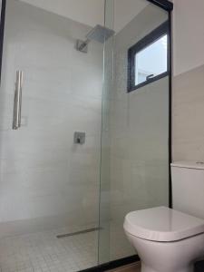 ein Badezimmer mit Toilette und Glasdusche in der Unterkunft López in Capiatá