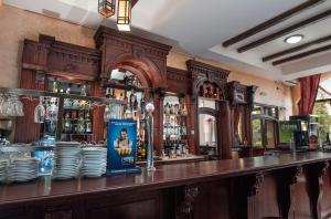 a bar with a counter with plates and alcohol at Pensiunea Siva in Horezu