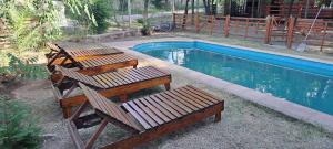 three wooden benches sitting next to a swimming pool at Cabañas El Oasis del Peñón in Casa Grande