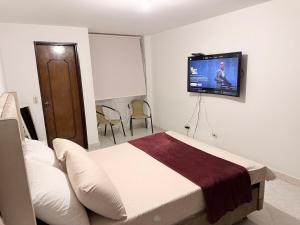 a bedroom with a bed and a flat screen tv on the wall at Alojamiento Laureles la 33 in Medellín +2 photos