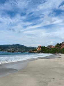a beach with people swimming in the water at Hotel Familiar El Dorado in Zihuatanejo
