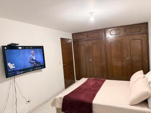 a bedroom with a bed with a flat screen tv on the wall at Alojamiento Laureles la 33 in Medellín