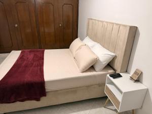 a bedroom with a bed with a wooden headboard and a table at Alojamiento Laureles la 33 in Medellín