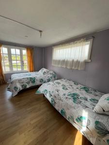 a bedroom with two beds and two windows at Espaciosa casa familiar en Queule in Nehuin