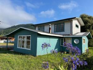 a blue and white house with flowers in front of it at Espaciosa casa familiar en Queule in Nehuin