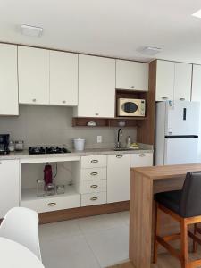 a kitchen with white cabinets and a white refrigerator at Apartamento alto padrão in Xangri-lá