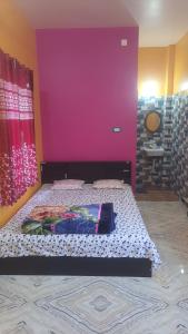 a bedroom with a bed with a purple wall at Amullya Kanan Villa in Haldia