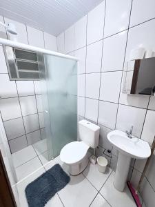 a white bathroom with a toilet and a sink at Apartamento Confortável Próx Unesp in Botucatu