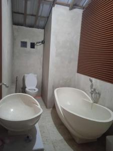 a bathroom with a sink and a tub and a toilet at Umah Pororo in Karangasem