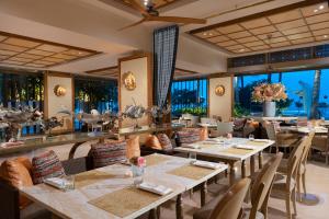 ein Restaurant mit Tischen und Stühlen und großen Fenstern in der Unterkunft Mulia Resort in Nusa Dua