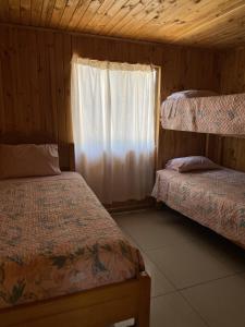 a bedroom with two beds and a window at Cabañas Anny 2 in Linares